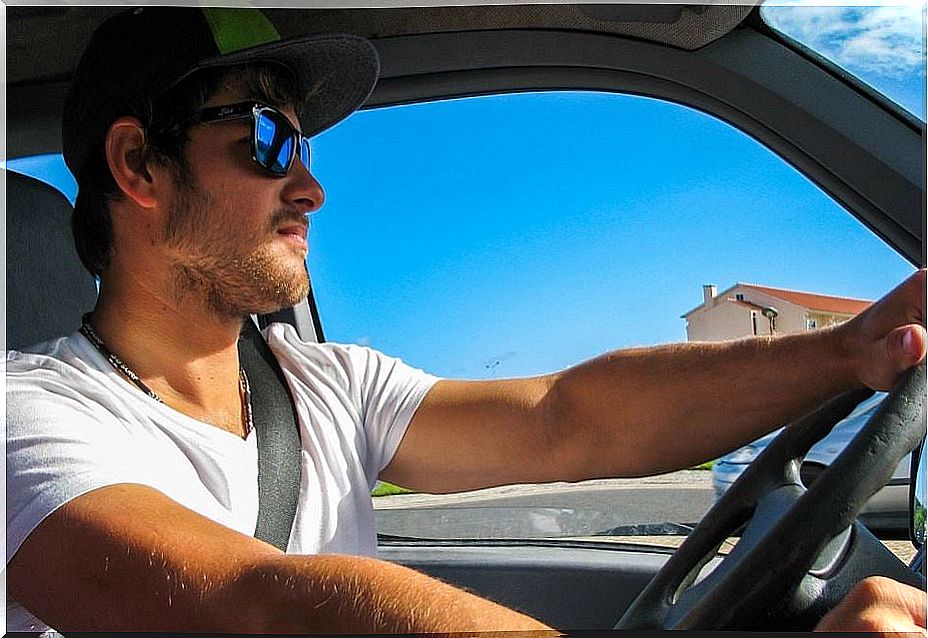 Young guy driving with sunglasses.